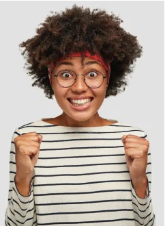 Une femme souriante, les poings levés en signe de motivation